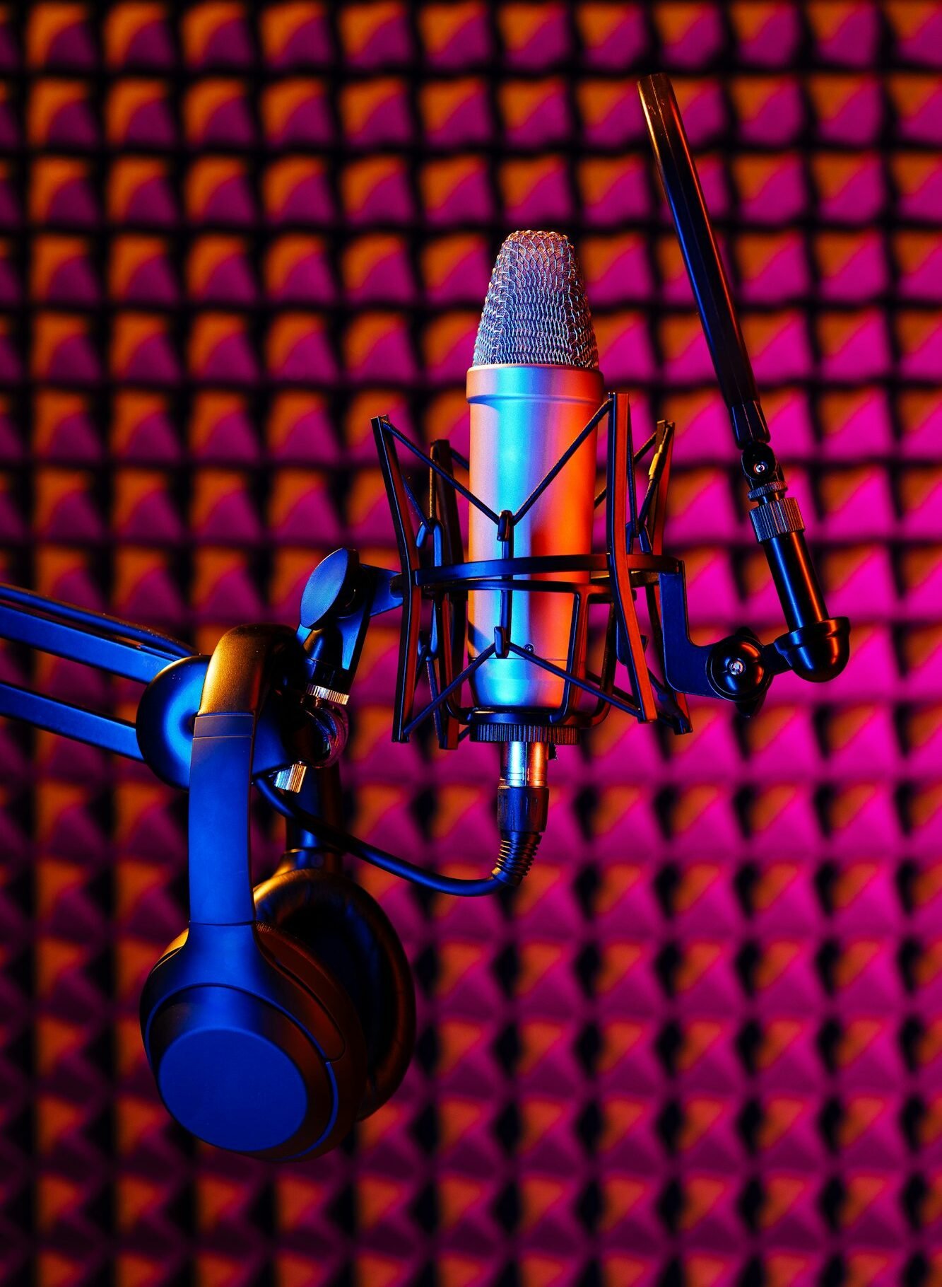 Professional studio microphone against acoustic foam panel background in neon light